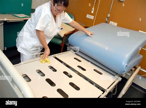 Nurse cleaning hospital bed. Nurse using a cloth to clean the base of a ...