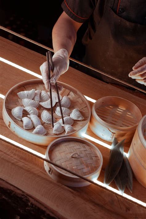 Person Preparing Dumplings Using Chopsticks on Bamboo Steamer · Free ...