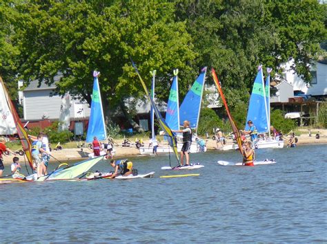 several people on surfboards with sail boats in the water