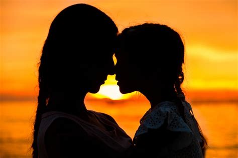 Silhouette of mother with her daughter standing and sunset | Free Photo