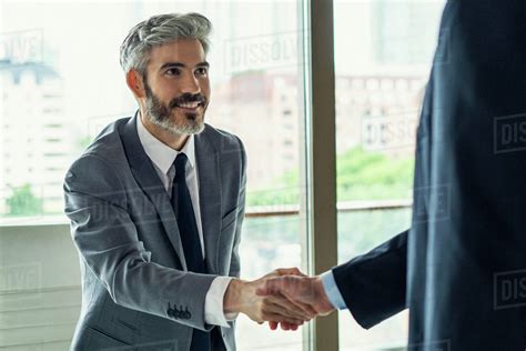 Businessmen shaking hands in office - Stock Photo - Dissolve