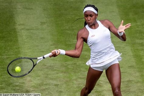 a woman swinging a tennis racquet at a ball on a grass covered court