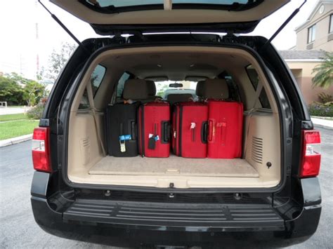 the back end of a van with luggage in it's trunk and two red suitcases