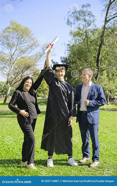 Young Recently Graduated Boy, Dressed in Cap and Gown, with His Degree in Hands, Celebrating ...