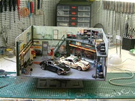 a model of a garage with two cars parked in front of it and tools ...