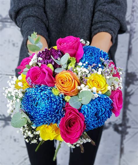 a woman holding a bouquet of colorful flowers