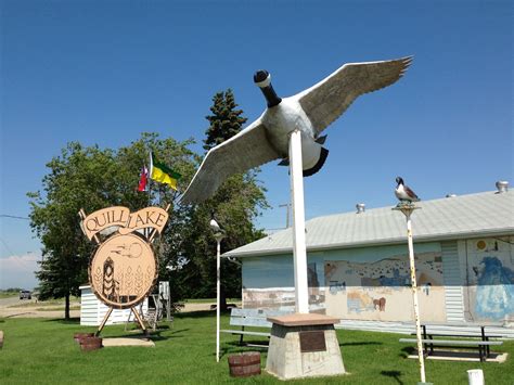 a large bird statue sitting on top of a lush green field next to a building