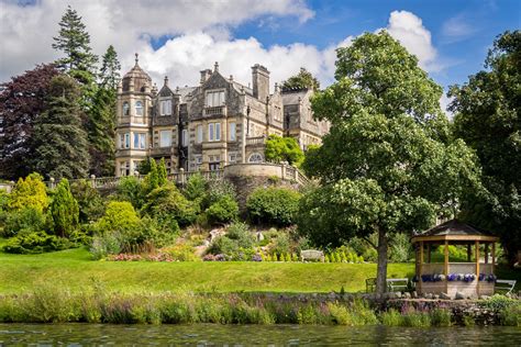 a large building sitting on top of a lush green hillside next to a lake and forest