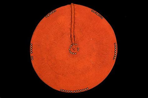 A Zulu Traditional Woman's Large Circular Red Painted Woven Fibre Hat Decorated With Brass Studs