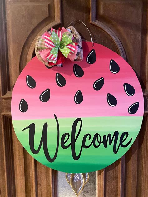 a watermelon painted welcome sign hanging on a wooden door with the ...