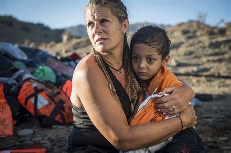 A European volunteer holds a refugee child on her arms after a boat carrying refugees arrived in ...