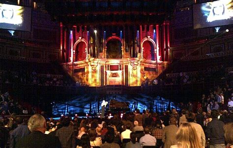 a large group of people are sitting in front of a stage with lights on it