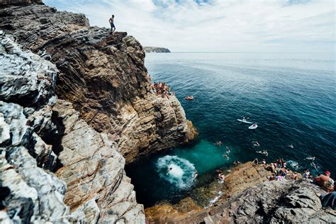 people are swimming in the ocean near some cliffs