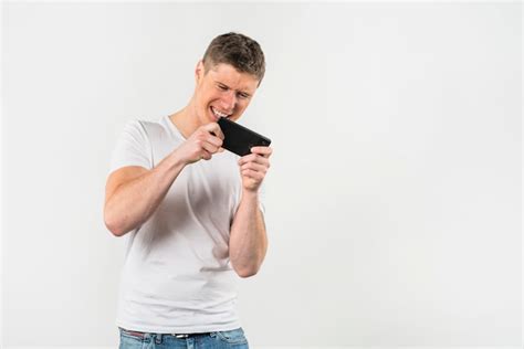 Free Photo | Young man playing video game on mobile phone against white backdrop