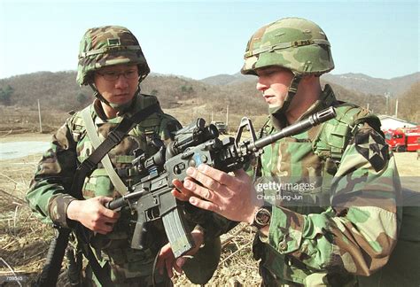 A U.S. and South Korean soldier inspect their weapons as they... News ...