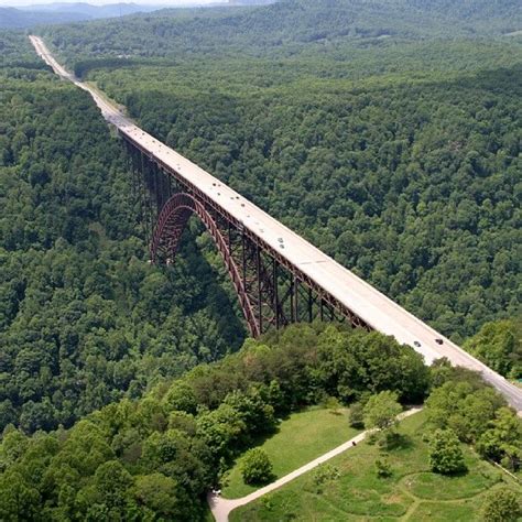 an aerial view of a large bridge in the middle of a forested area with cars driving on it