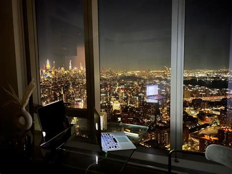 a laptop computer sitting on top of a desk in front of a window at night