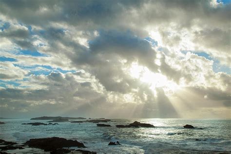 Sun Shining Through Clouds Over Beach by Henglein And Steets