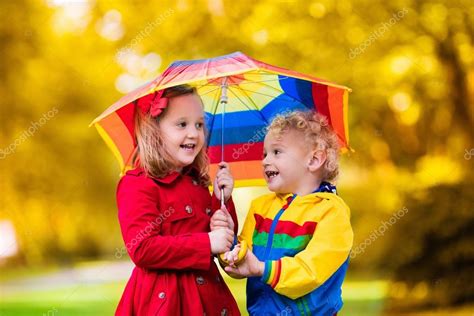 Kids playing in the rain under colorful umbrella Stock Photo by ...