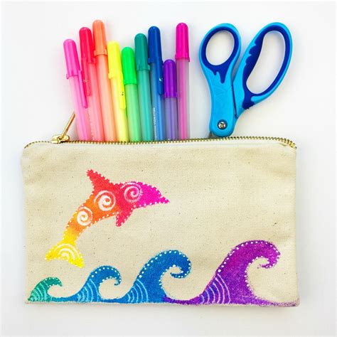 a pencil case with scissors and markers in the shape of an ocean wave on it