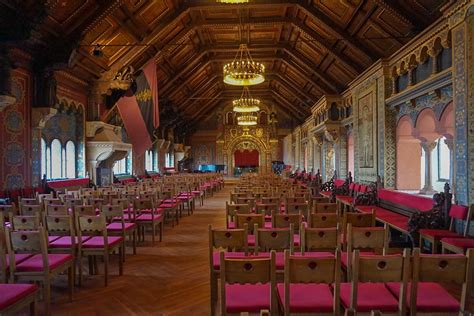 rows of wooden chairs are lined up in an ornately decorated room with chandeliers