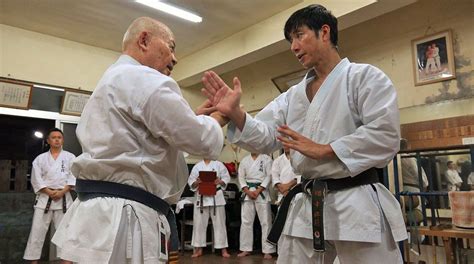 two men in white karate uniforms standing next to each other with their hands together while ...