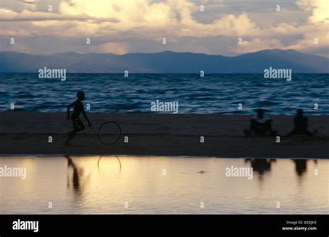 Silhouetted boy chasing hoop on Lake Malawi beach at sunset, Malawi, Africa Stock Photo - Alamy