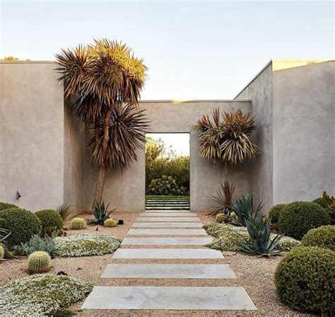 an entrance to a desert style home with cactus and succulents in the foreground