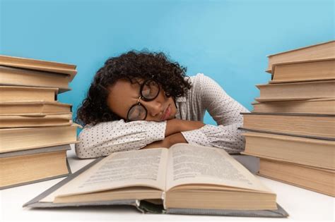 Premium Photo | Exhausted african american female student sleeping on desk among stacks of books ...