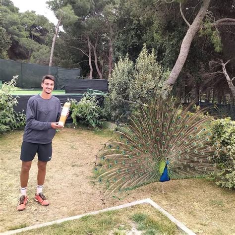 Lorenzo Sonego with his ATP 250 Cagliari trophy next to a peafowl, very ...