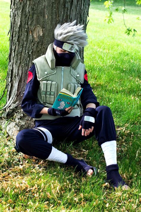 a man sitting under a tree with a book in his hand and wearing a mask