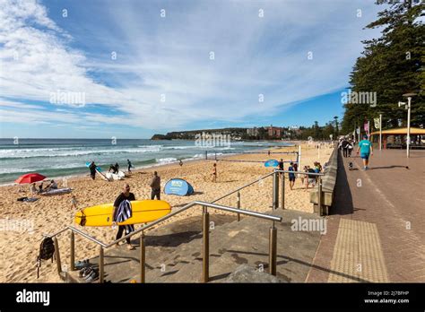 Manly Beach in Sydney,autumn weather and surfer leaves the beach alongside beach volleyball ...