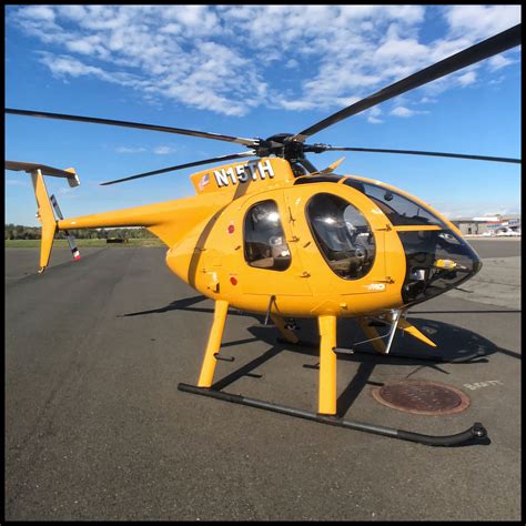 a yellow helicopter sitting on top of an airport tarmac next to a blue sky