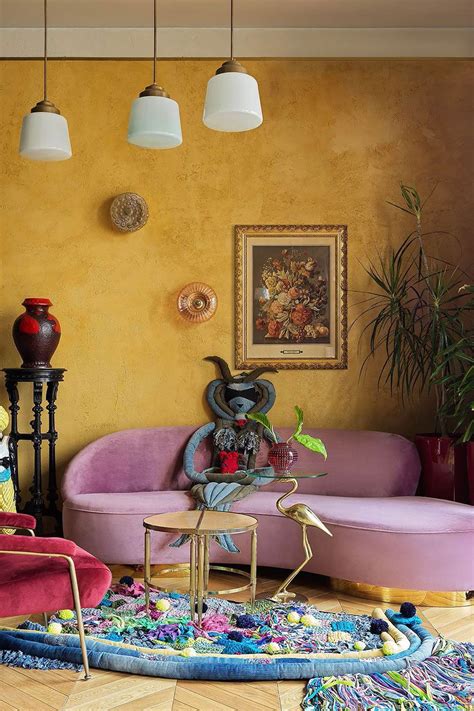 a living room with yellow walls and pink couches, colorful rugs and potted plants