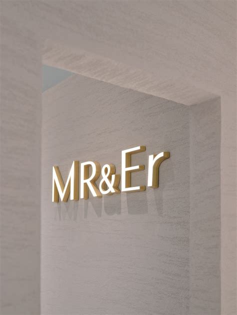 the logo for mr and er is illuminated in gold on a white wall behind it