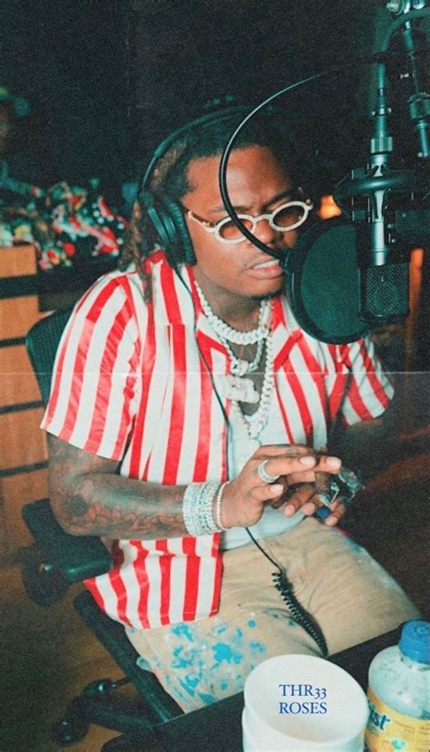 a man sitting in front of a microphone with headphones on his ears and wearing a red and white ...