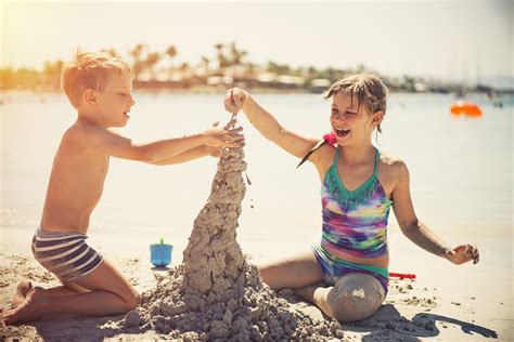 Kids building a sandcastle on a sunny beach - DB Wood