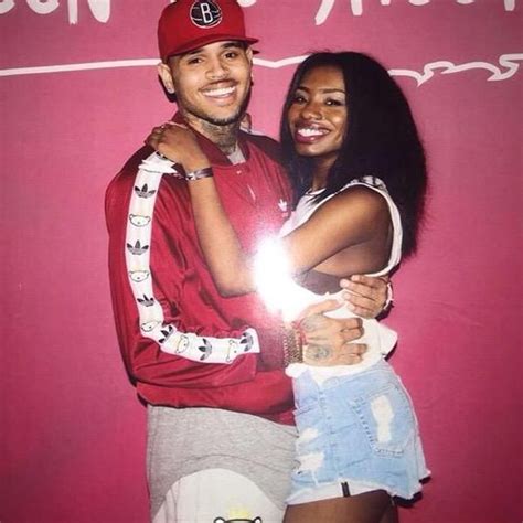 a man and woman hugging in front of a pink wall