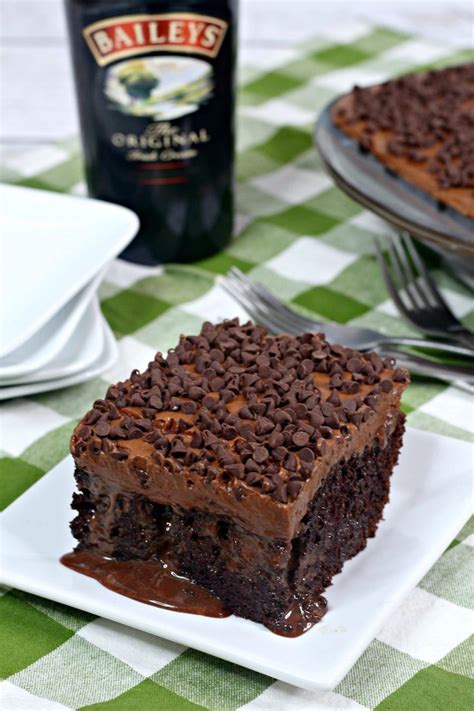 a slice of chocolate cake on a plate with a bottle of bailey's in the background