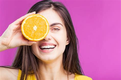 Premium Photo | Portrait of beautiful brunette smiling girl holding cutted orange fruit near her ...