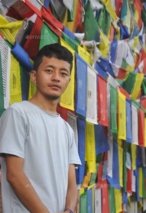 Photo of a Ladakhi young guy looking at camera, standing against Buddhist prayer flags Stock ...