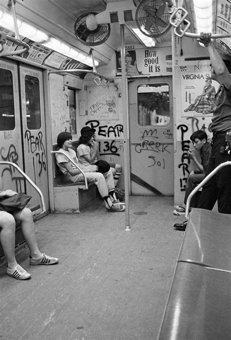 black and white photograph of people sitting on subway cars with graffiti all over the walls