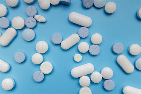 Small White And Blue Painkiller Pills On A Blue Background Stock Photo - Download Image Now - iStock