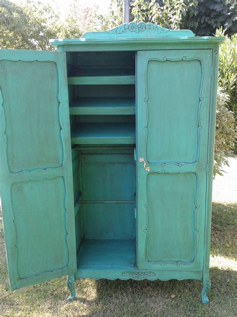 an old green cabinet is sitting in the grass with it's doors open and shelves closed