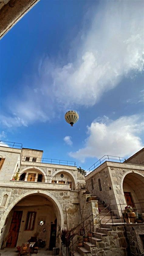 a hot air balloon flying in the sky over a building with stone arches ...