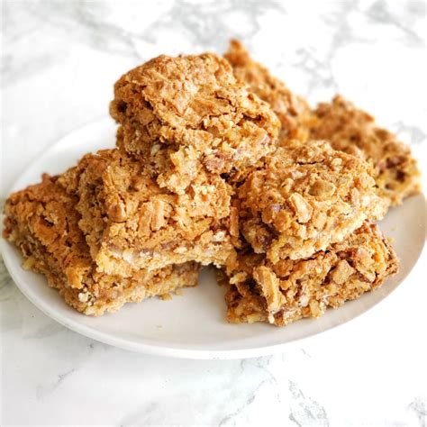 Coconut Pecan Dream Bars piled on a white plate on a white marble counter