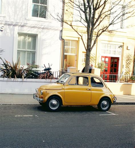 an old yellow car parked in front of a building