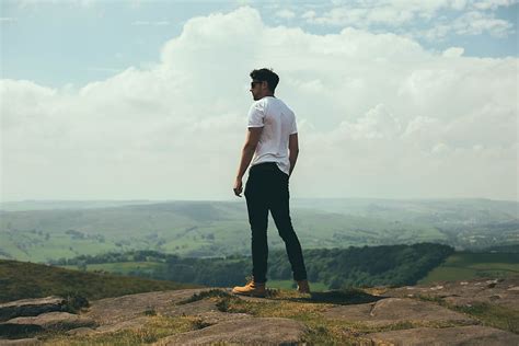 HD wallpaper: man standing on bolder overlooking the hills and mountains, standing man in white ...