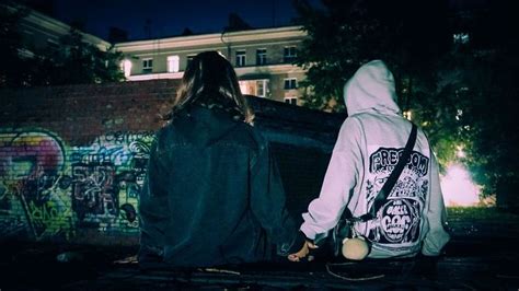 two people holding hands in front of a wall with graffiti on it and one ...