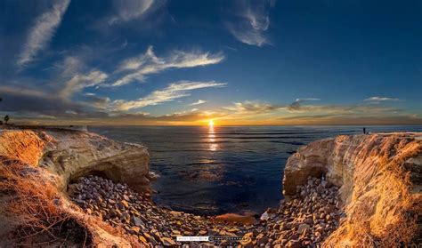 the sun is setting over the ocean and rocks